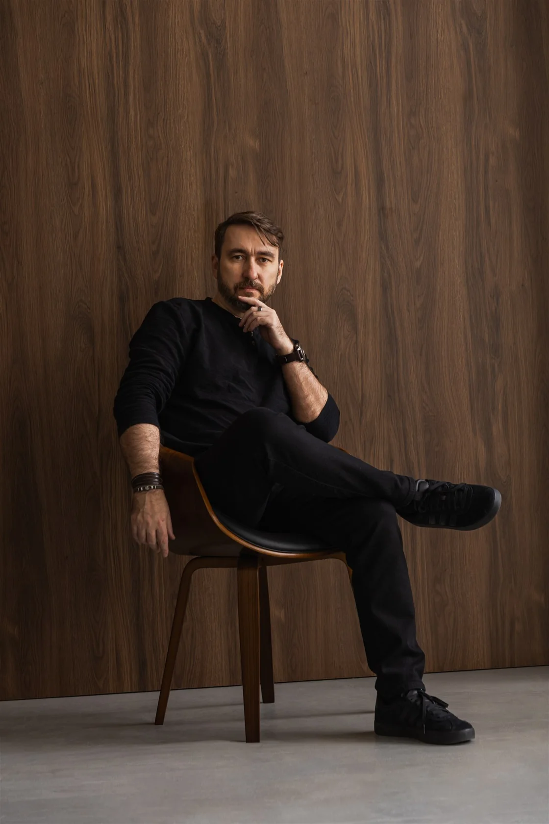 Portrait of Krystian Wydro seated against a wooden wall